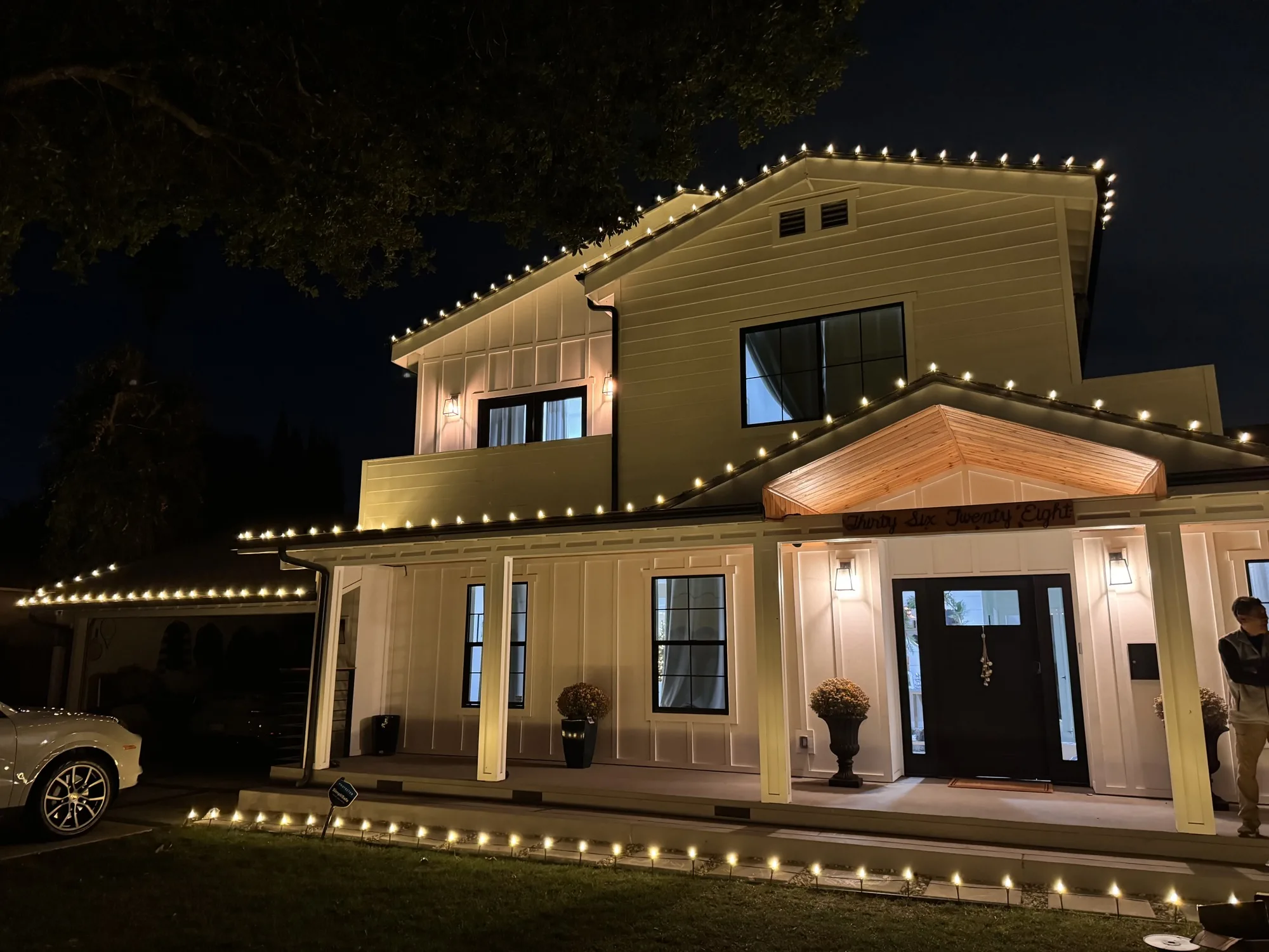 Modern farmhouse with warm-white roofline Christmas lights by Bee Merry