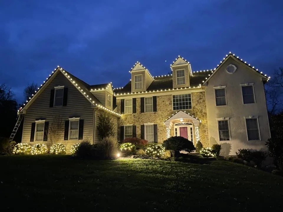Colonial home with warm-white roofline Christmas lights by Bee Merry